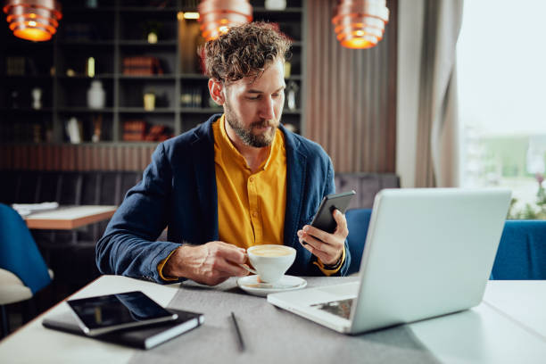 Person using mobile device with coffee and laptop